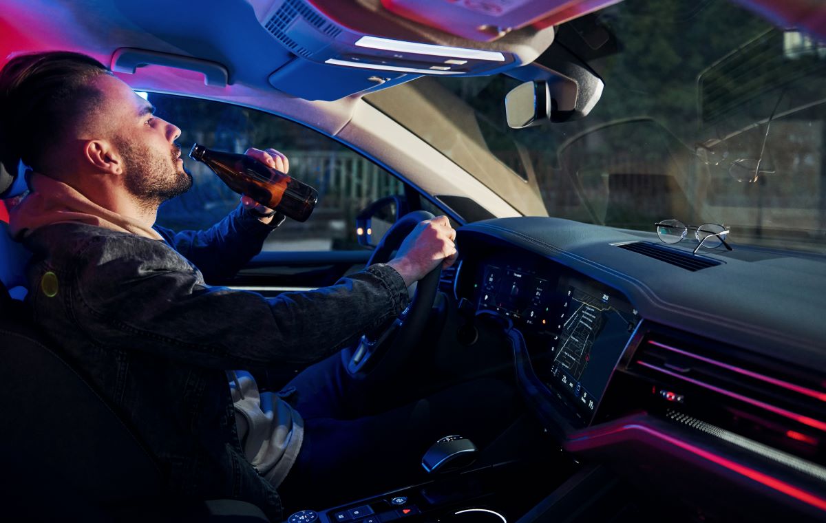 man drinking alcohol while driving a car