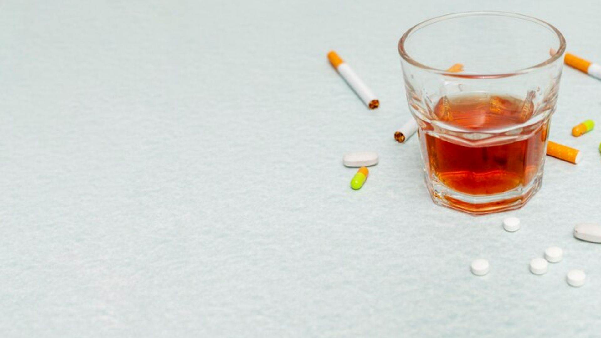 A glass of alcohol and cigarettes in copy space highlights the need for breathalysers for testing other substances.