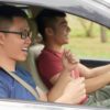 The side view of two men sitting in a car highlights the role of breathalysers for ride-share drivers in ensuring passenger safety.