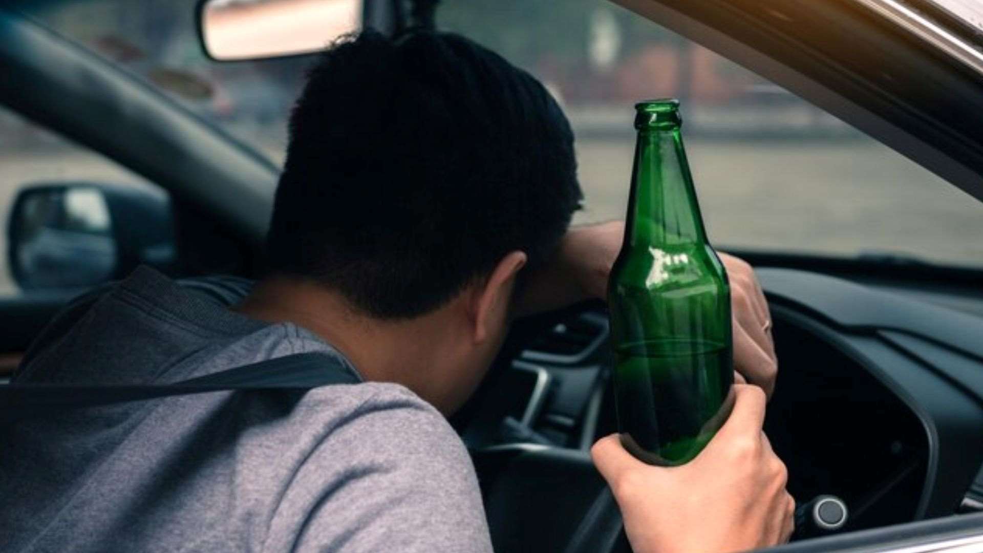 The rear view of a man sitting in a car highlights the importance of international drink-driving laws in ensuring road safety.