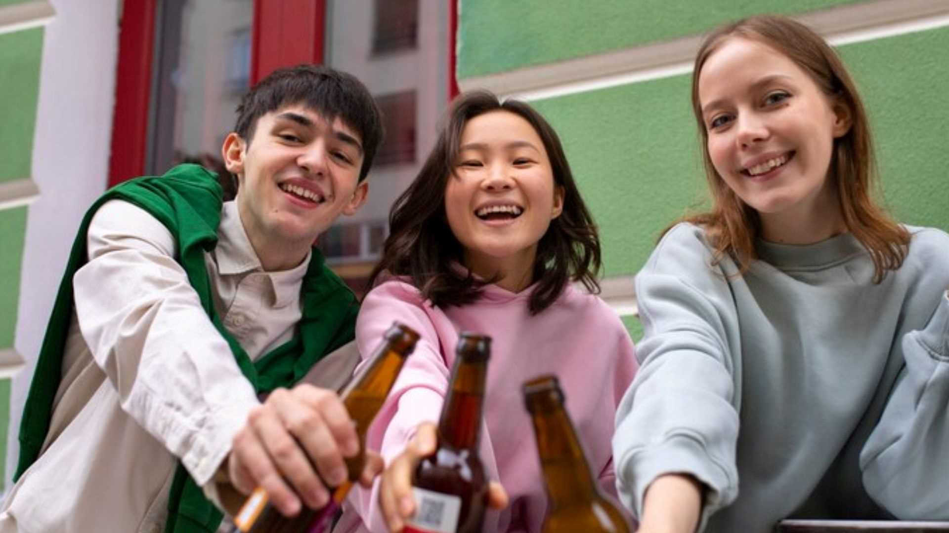 Three friends drinking beer, embodying responsible drinking in universities on a vibrant campus setting.
