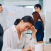 A young Chinese businesswoman looks stressed while working, highlighting how frequent breathalyser tests can help maintain a safe and focused workplace.