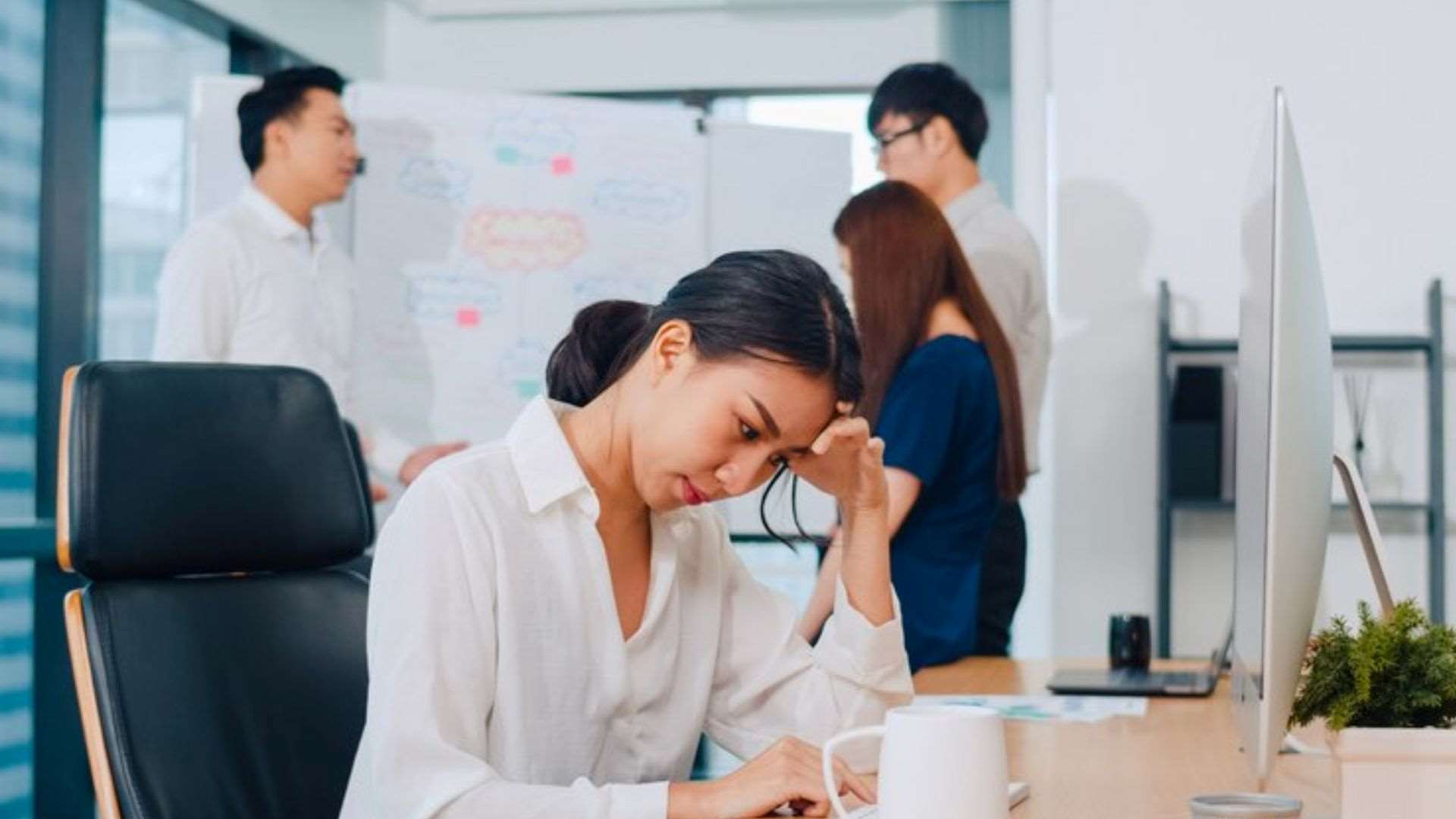A young Chinese businesswoman looks stressed while working, highlighting how frequent breathalyser tests can help maintain a safe and focused workplace.