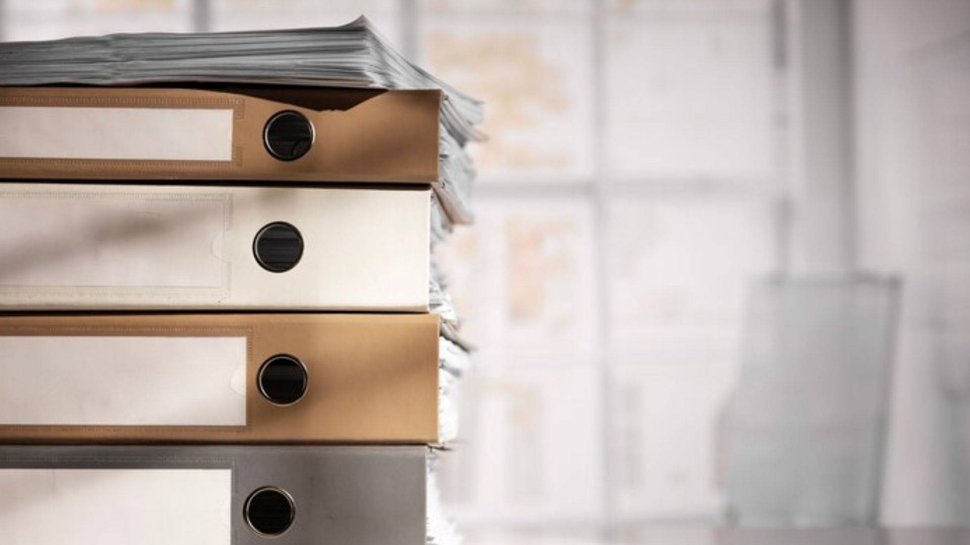 A stack of binders and documents sits on an office desk, reflecting workplace policies and employee alcohol screening records.
