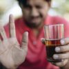 A man holding a glass appears thoughtful, symbolizing the connection between breathalysers and medication interactions.