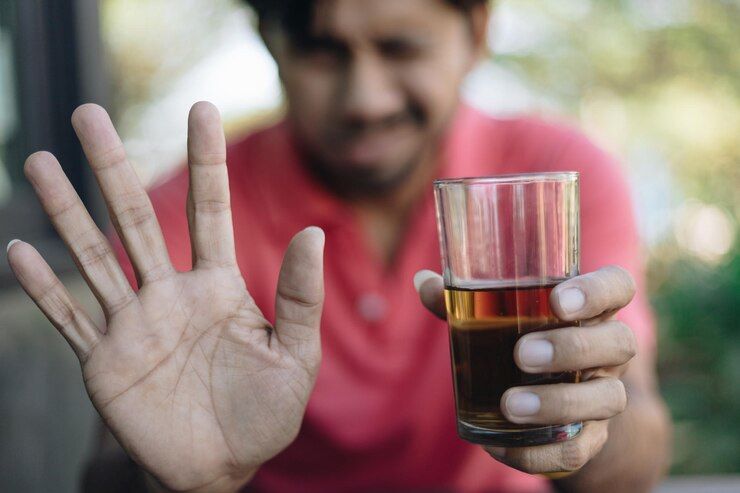 A man holding a glass appears thoughtful, symbolizing the connection between breathalysers and medication interactions.