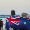 A couple enjoys the beach with their blue English Stafford dog, reflecting breathalyser use during Australian holidays.