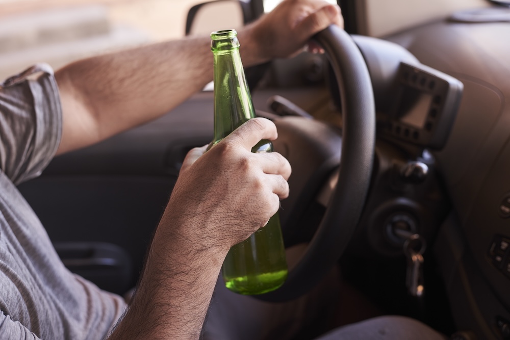 A bottle of beer in a man's hands, representing How Urban Mobility Services Are Encouraging Driver Breathalyser Self-Checks