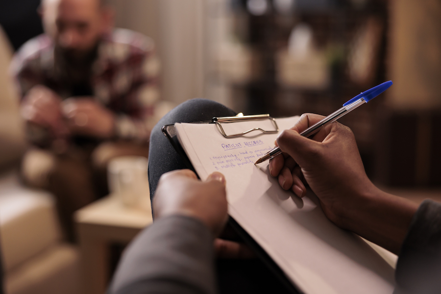 male psychologist takes notes after client uses personal breathalyser