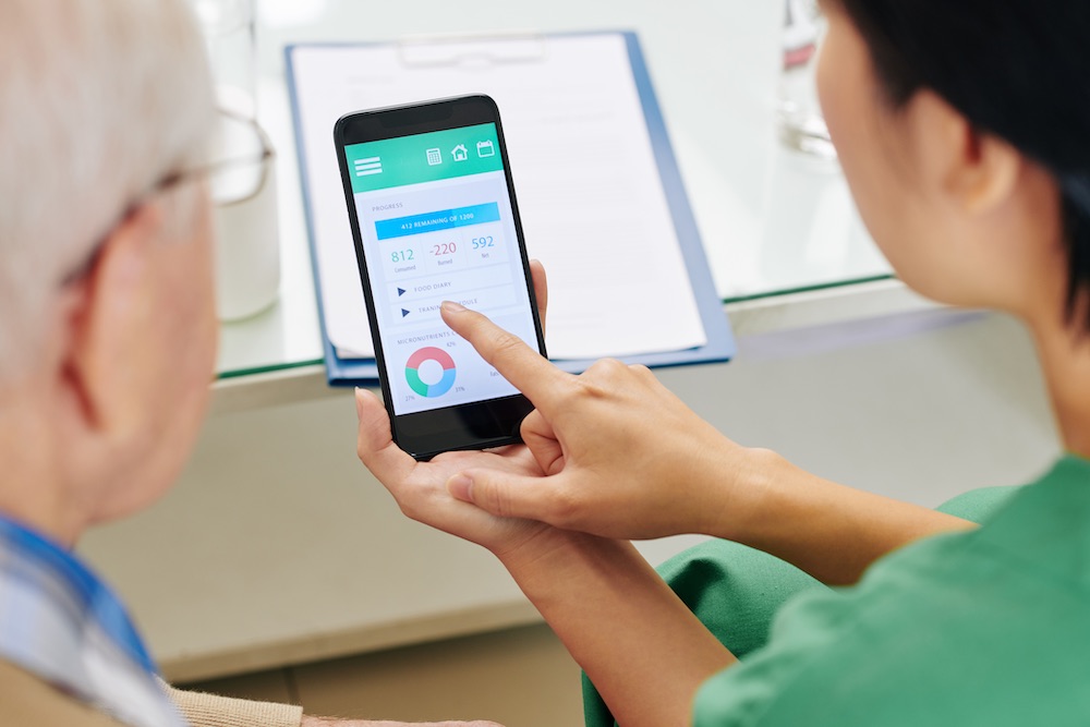 nurse showing patient how to use smartphone-compatible breathalyser